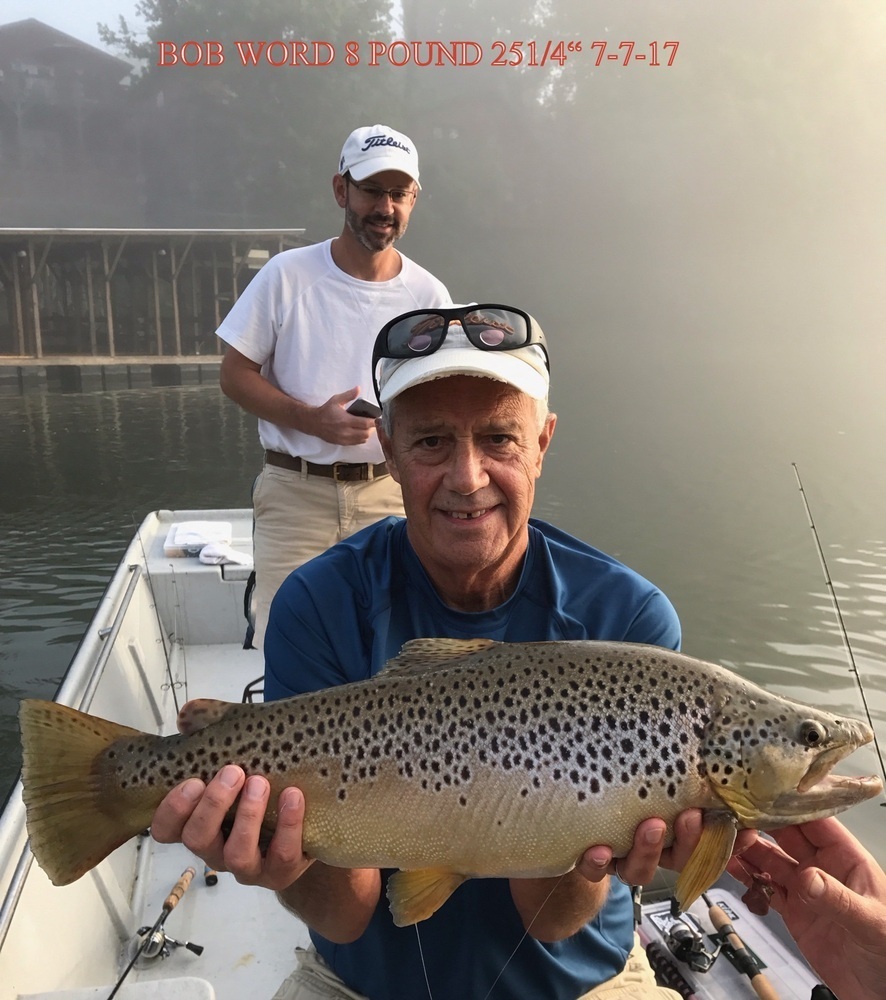 2 men on boat. One holding a fish.